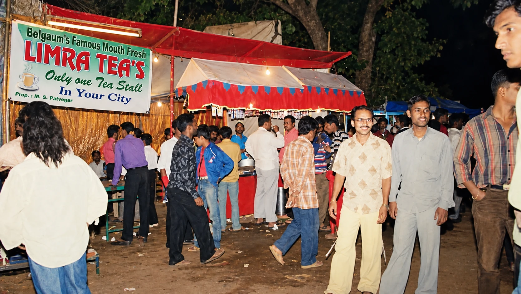 The original Limra Tea's stall in Belgaum at night, with a crowd of customers under a red canopy and a banner reading 'Only one Tea Stall in Your City'