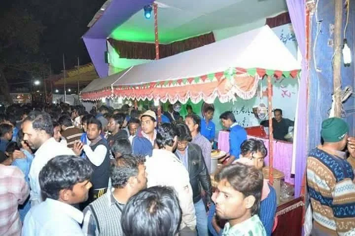 A busy crowd in front of a Limra stall with a green and red canopy at night